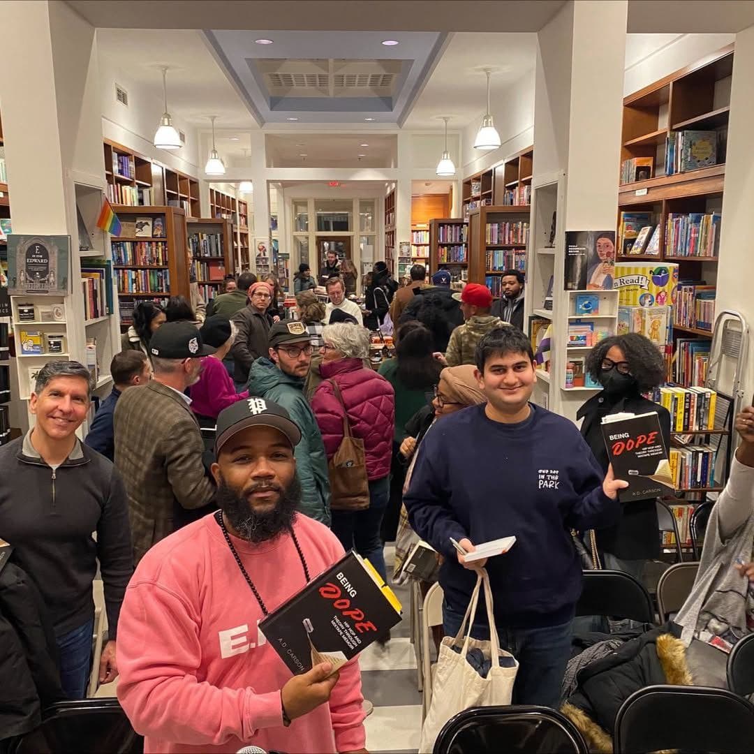 Readers holding copies of Being Dope by A.D. Carson at a packed bookstore launch event